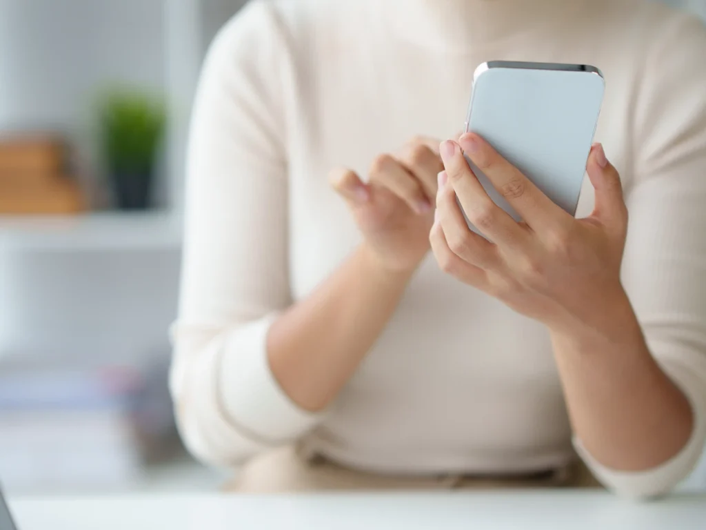 Primer plano de manos usando un smartphone para gestionar el chat y las ventas de una cuenta de Fansly
